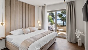 Un dormitorio moderno con una cama grande, vistas al mar y un balcón con mobiliario exterior.