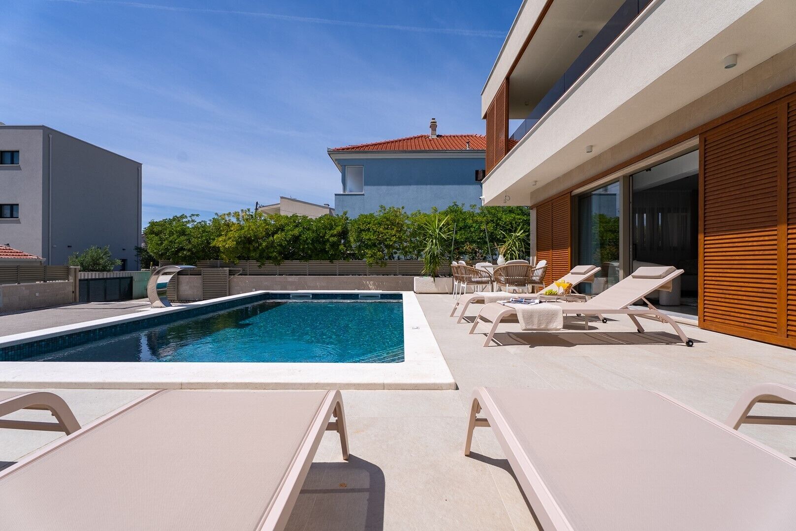 Ein moderner Poolbereich im Freien mit Liegestühlen und freiem Blick auf die umliegenden Gebäude.