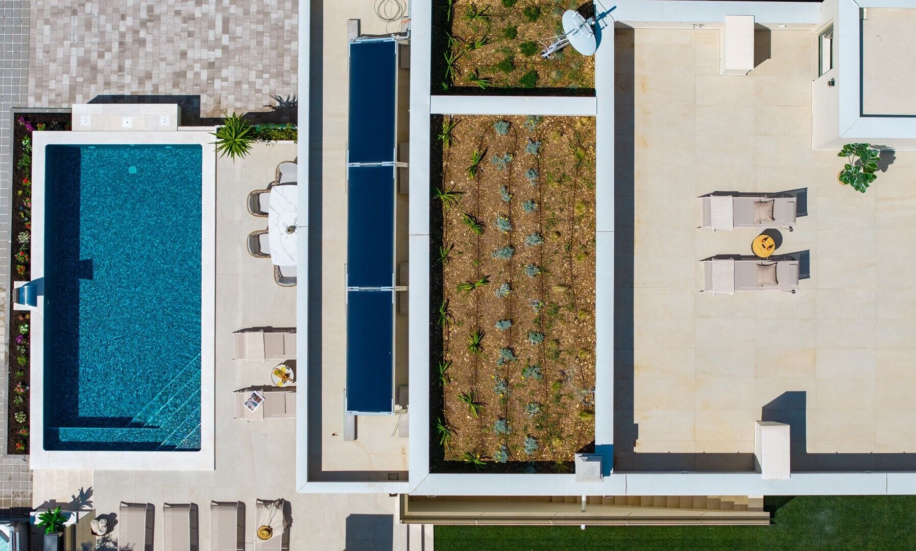 An aerial view of a modern hotel with a swimming pool, outdoor seating, and a garden area.