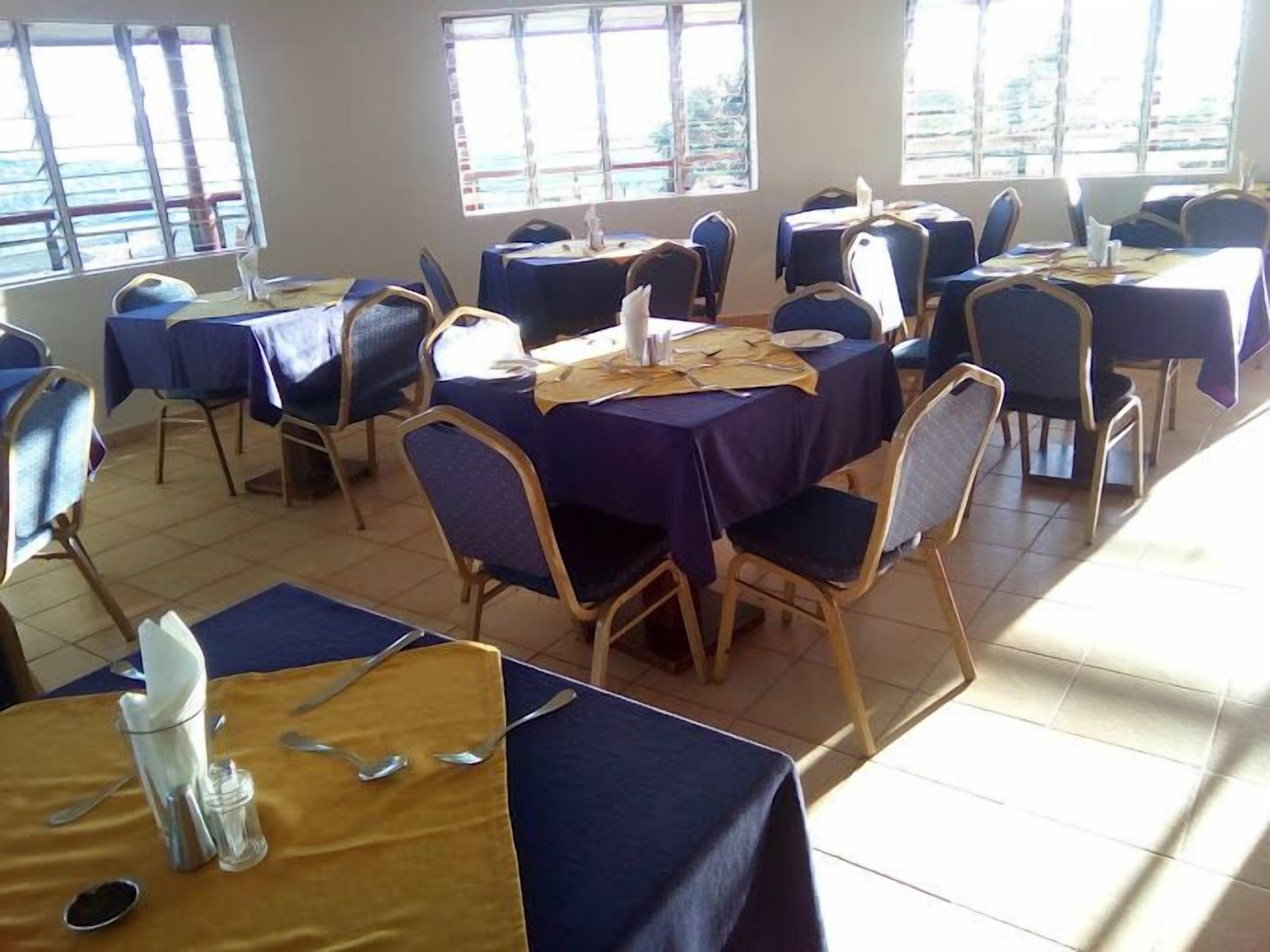 A dining area with tables and chairs, large windows, and a tiled floor.
