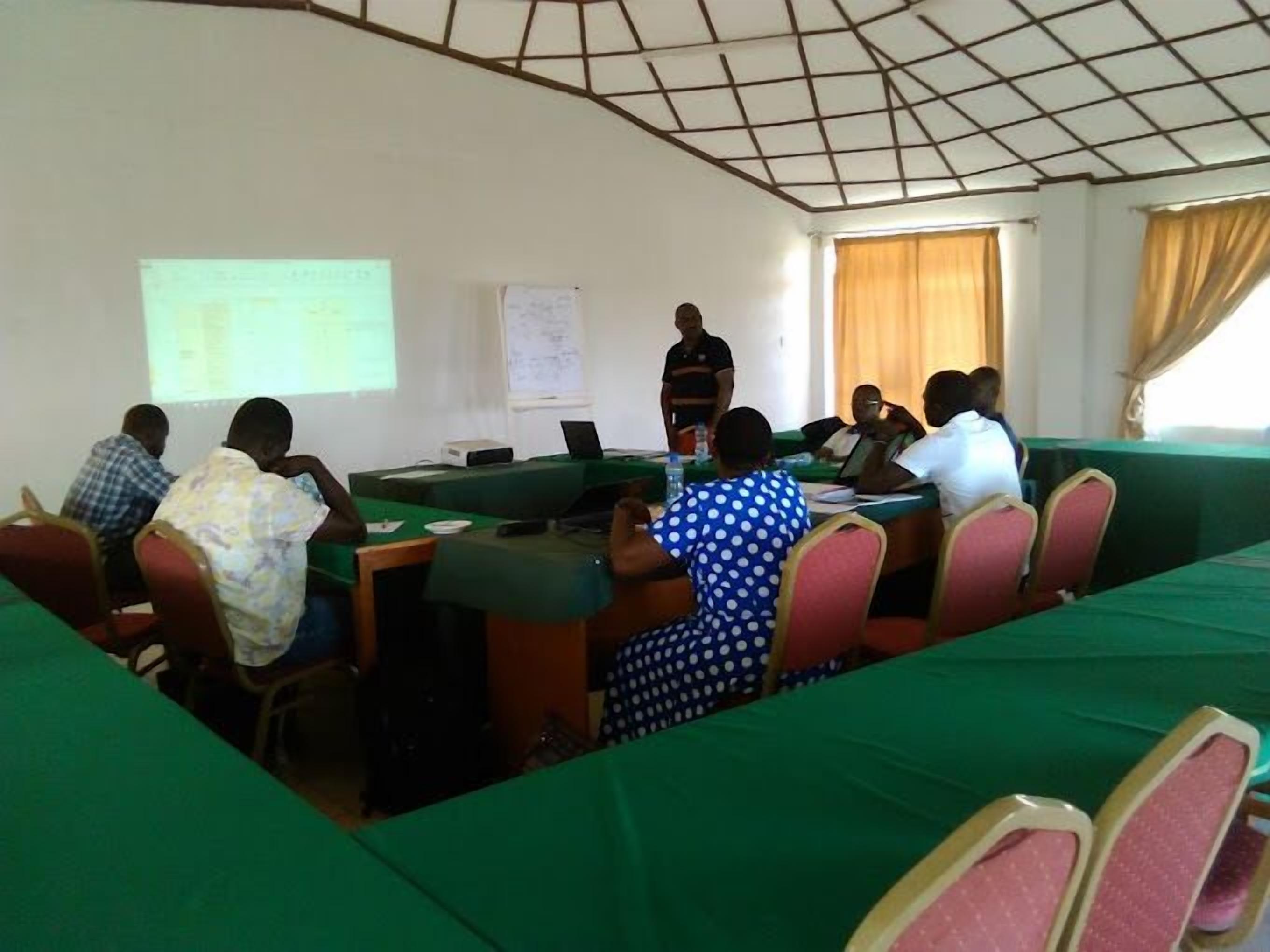 A conference room with a long table, chairs, and a projector screen.