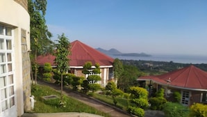 A residential area with houses featuring red roofs, surrounded by greenery and a clear view of the sea. - ACK Guest House Homabay (Homa Bay)