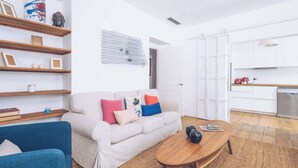 A living room with a sofa, coffee table, and shelves with decorative items.