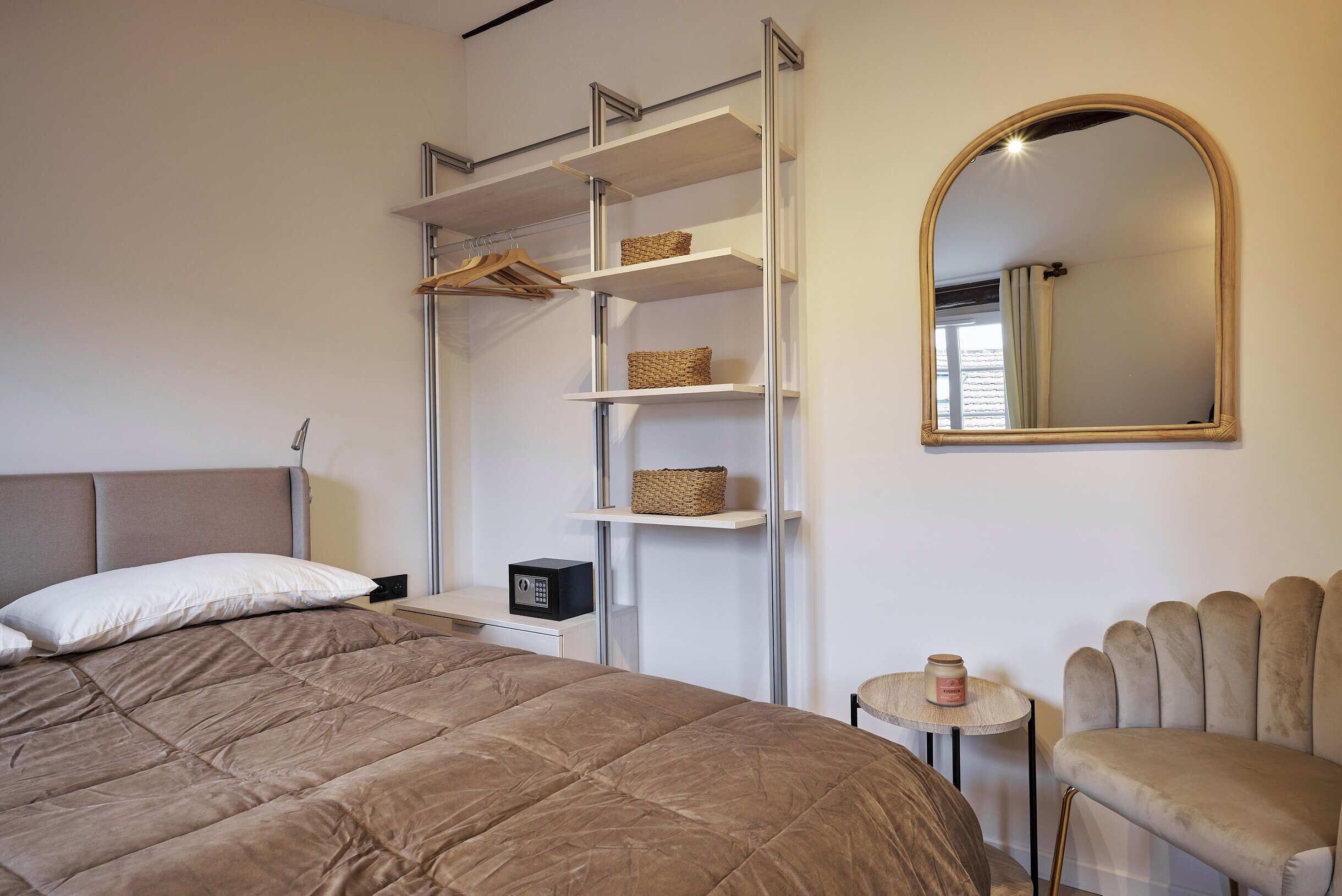Ein Schlafzimmer mit Bett, Kleiderschrank, Spiegel und einem kleinen Tisch.