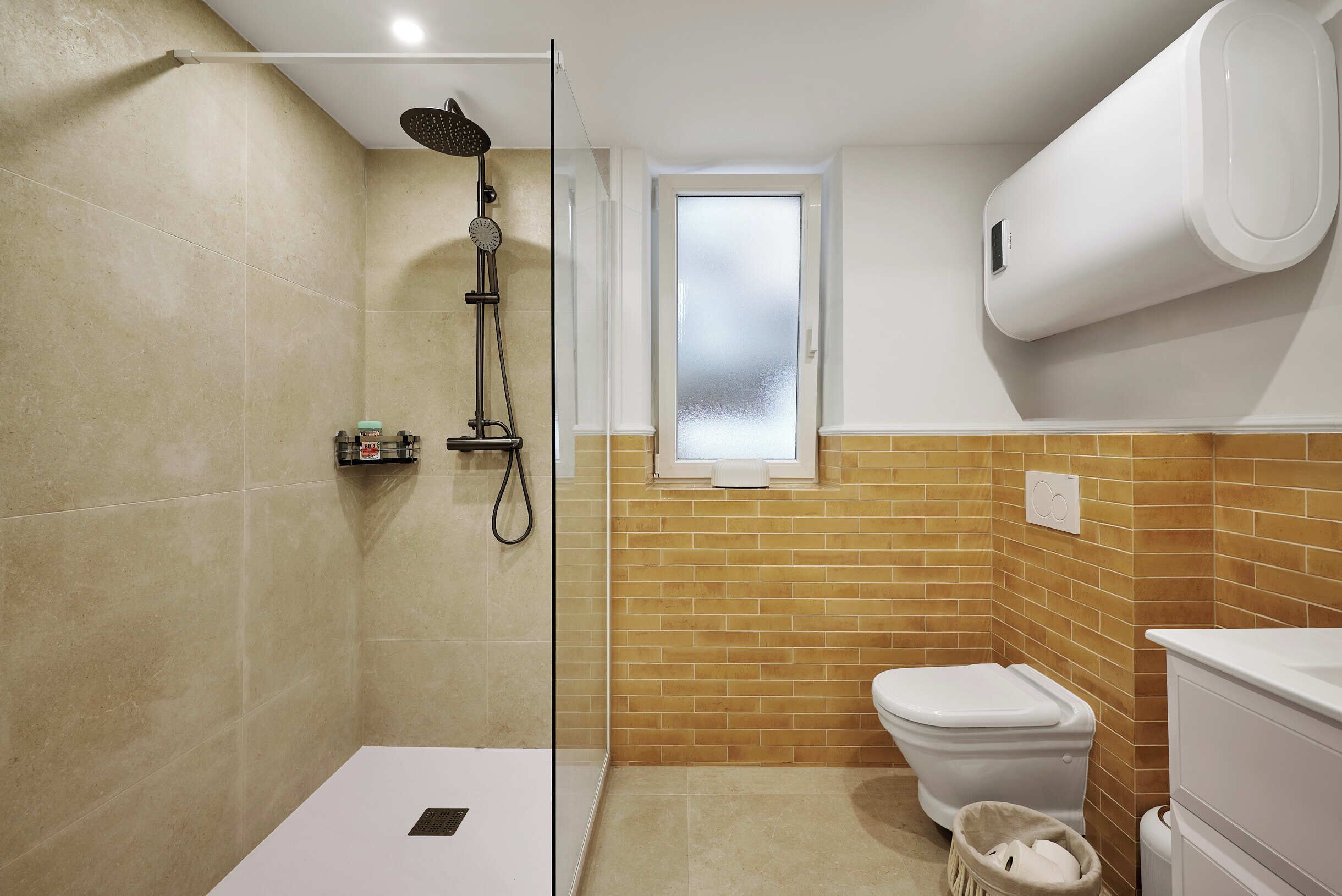 A bathroom with a glass-enclosed shower, a toilet, and a sink.