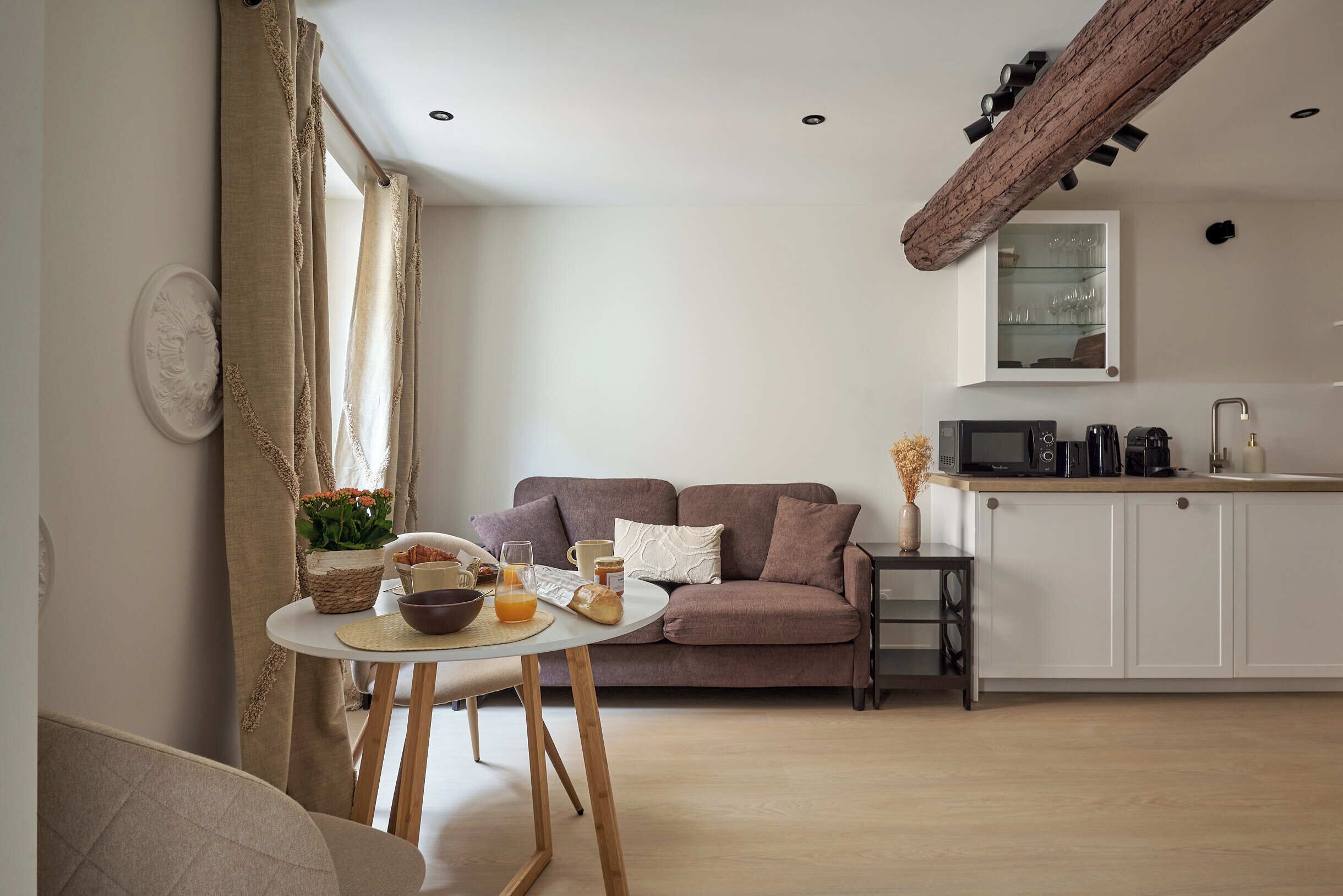A cozy living room with a sofa, a dining table with breakfast items, and a kitchen area with appliances.