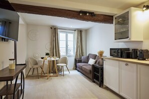 Un espace de vie compact comprenant un coin repas, un canapé et une kitchenette.