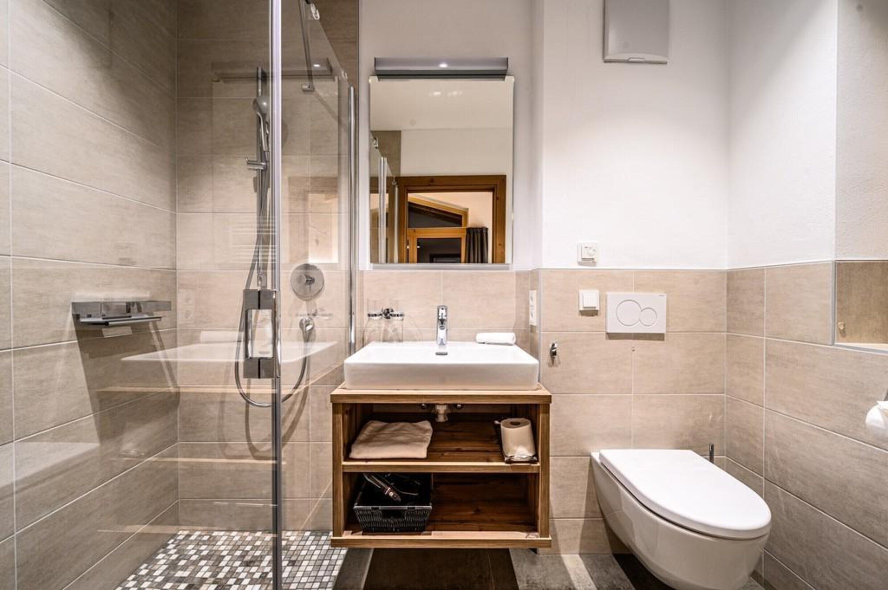 A modern bathroom with a glass shower enclosure, a sink with a wooden vanity, and a toilet.
