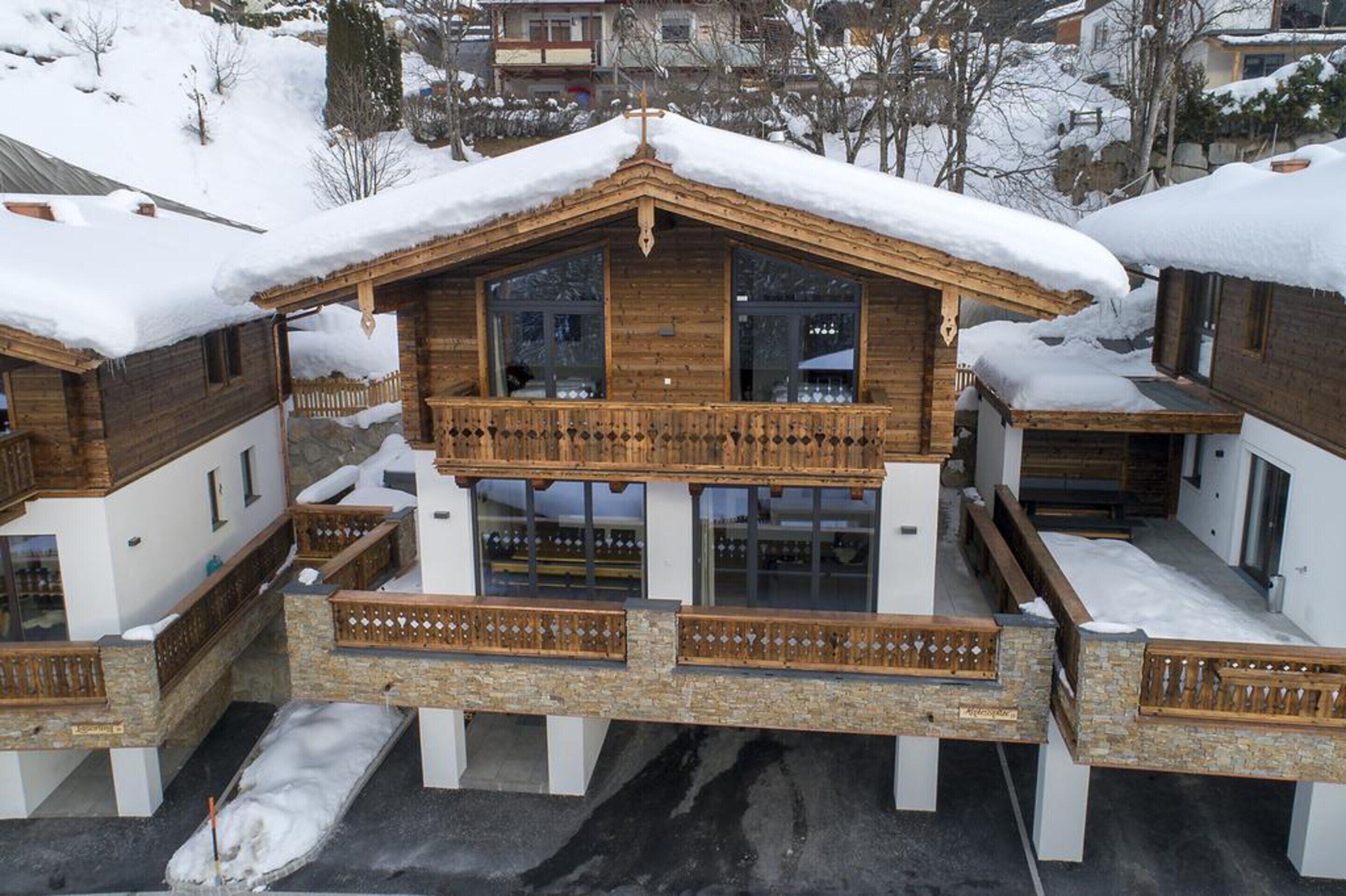 A wooden chalet with a balcony, surrounded by snow-covered houses.