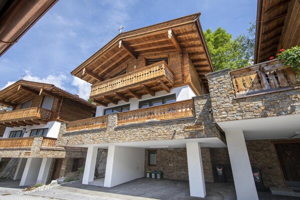 A traditional alpine-style building with wooden balconies and stone accents. - Family Chalet Escape in the Alps (Neukirchen am Grossvenediger)