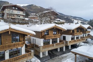A row of wooden chalets with balconies, set against a snowy mountain backdrop. - Family Chalet Escape in the Alps (Neukirchen am Grossvenediger)