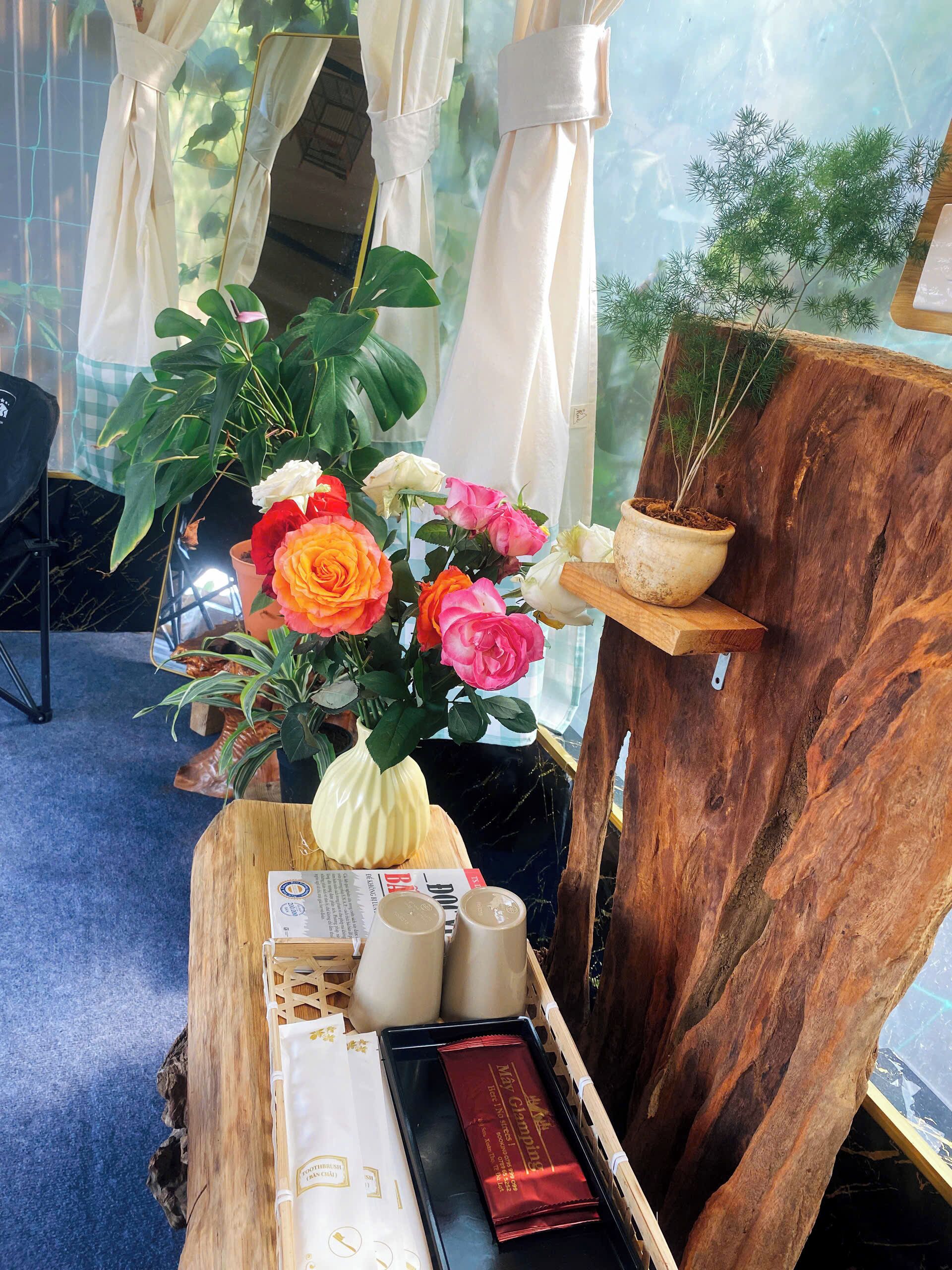 A wooden table with a vase of flowers, a tray with a red box, and a wooden stand with a plant.