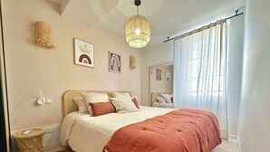 Ein Schlafzimmer mit einem Bett, einer Nachttischlampe, einer Wandleuchte und einem Fenster mit Vorhängen.