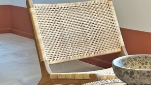 A wicker chair with a woven backrest and wooden legs, placed on a patterned mat. - La Pointe Rouge (Sanary-sur-Mer)