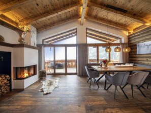 A spacious living room with a fireplace, large windows, and a dining area with modern furniture. - Chalet in Neukirchen Near Wildkogel Ski Slope (Neukirchen am Grossvenediger)