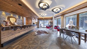 Un interno moderno con una scrivania di accoglienza in legno, sedie rosse e un pavimento decorato.