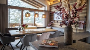 Un interno moderno con soffitto in legno, un'area pranzo con tavolo e sedie, e un vaso con piante essiccate su un bancone.