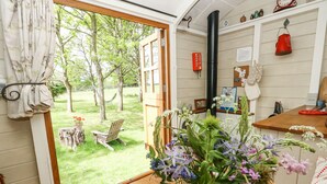 Eine Küche mit einem Holztisch, einer Topfpflanze und Blick auf einen grünen Garten durch eine offene Tür.