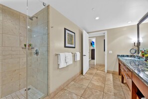 Une salle de bain moderne dotée d’une douche à parois de verre, d’un meuble-lavabo avec un plan de travail en marbre et d’une œuvre d’art encadrée au mur.