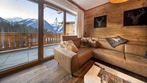 A modern living room with a large window overlooking a snowy mountain landscape.