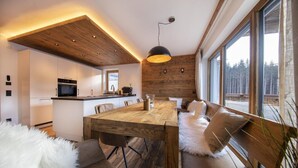 A modern kitchen with white cabinets, a wooden island, and a dining area with a wooden table and benches.