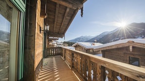 Un balcon en bois offrant une vue sur des montagnes enneigées et un ciel dégagé.