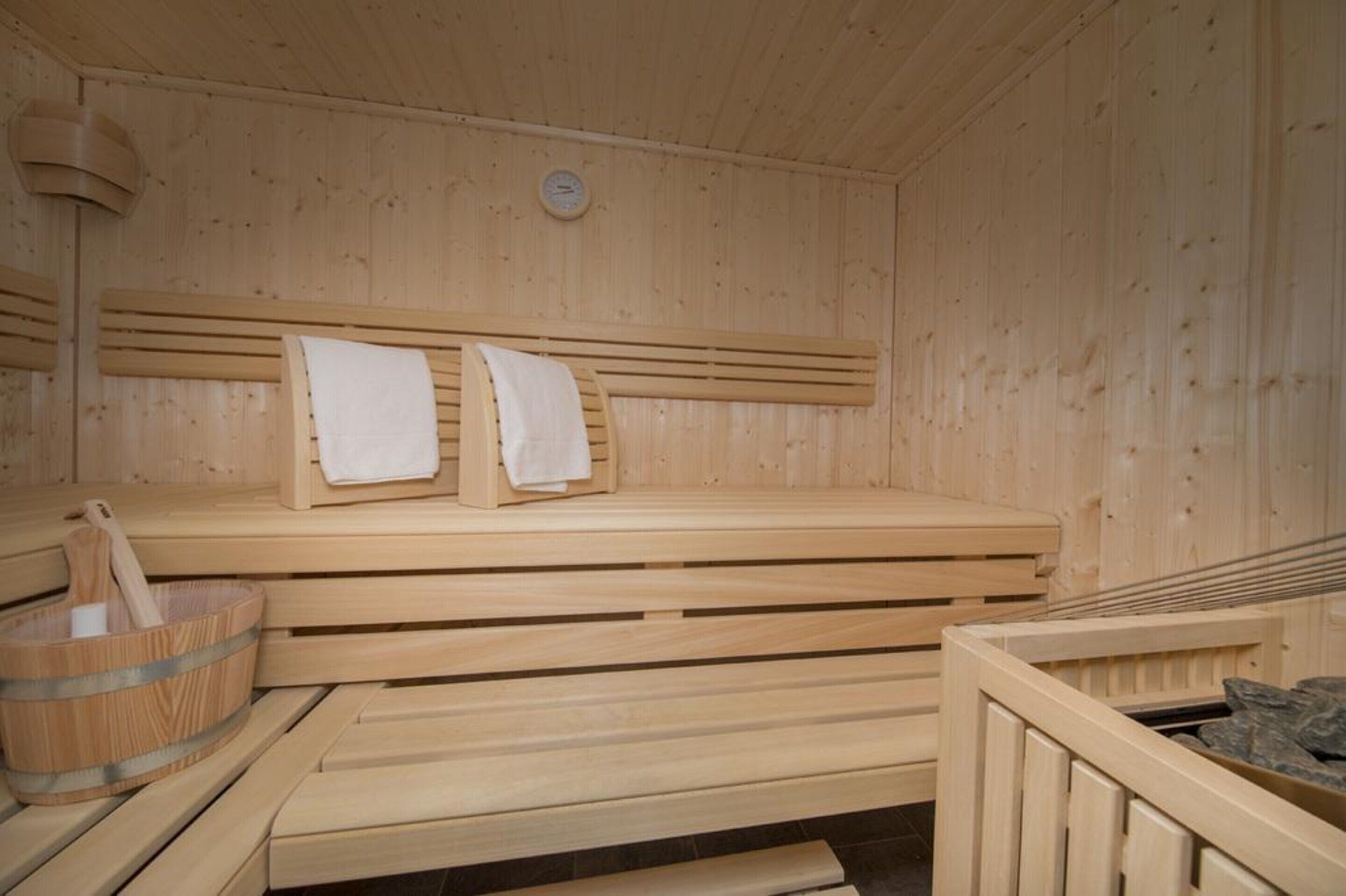 Een houten sauna met banken en een houten emmer.