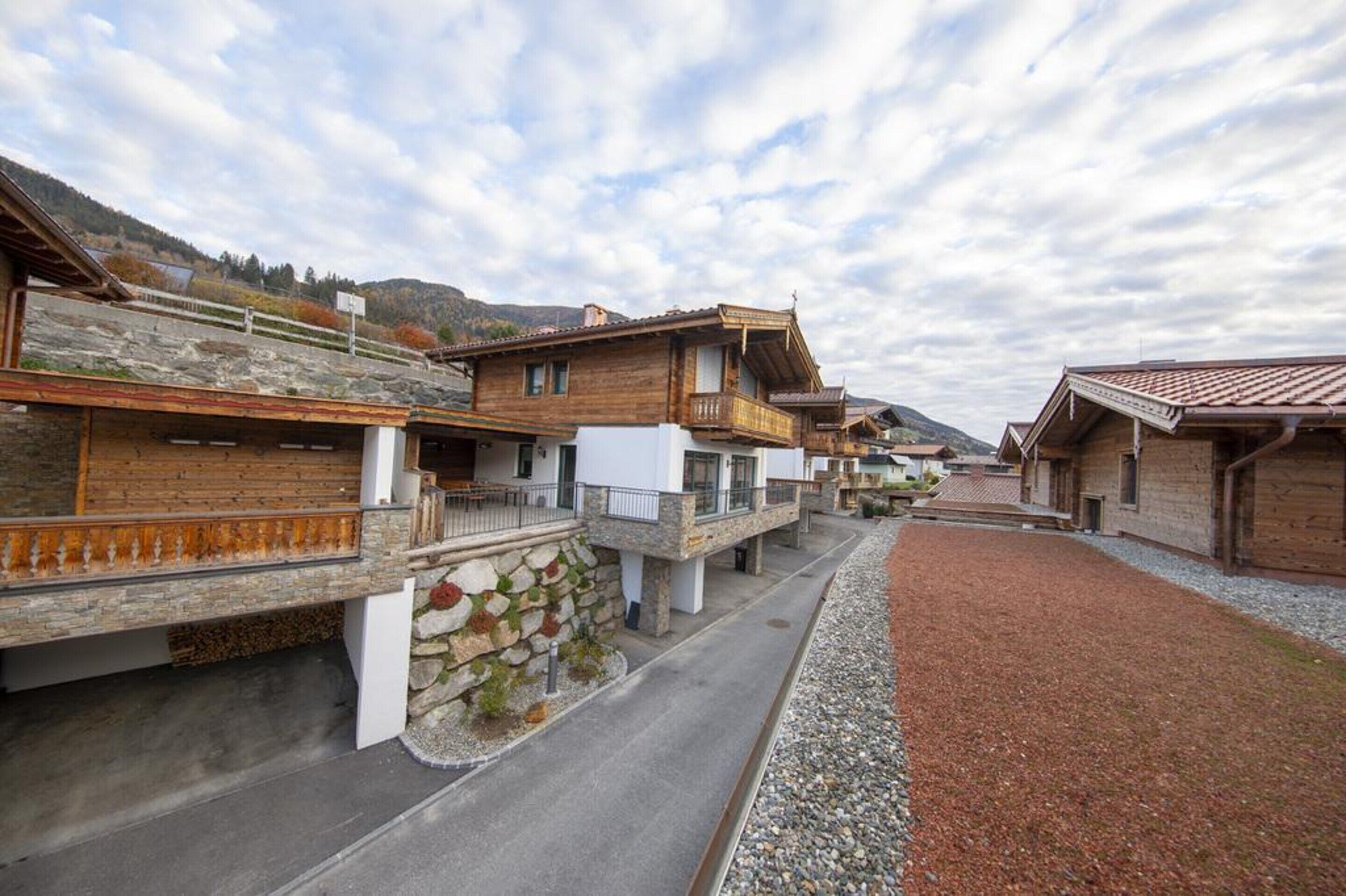 Una serie di case in legno tradizionali con fondamenta in pietra, una strada pavimentata e un sentiero sterrato.