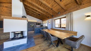 Une cuisine moderne dotée d’un îlot central, de planchers en bois et d’un coin repas avec une grande table et des chaises.