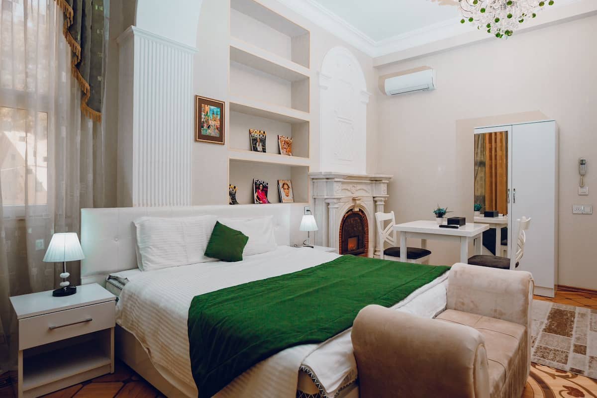 A hotel room with a large bed, a fireplace, a desk, and a mirror.