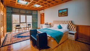 Un dormitorio con una cama grande, un escritorio, una silla y una ventana con vistas.