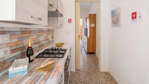 A modern kitchen with a wood-textured backsplash, a gas stove, and a countertop with a decorative leaf-shaped dish. - Casa Callisto AC vicino al mare (Porto Cesareo)