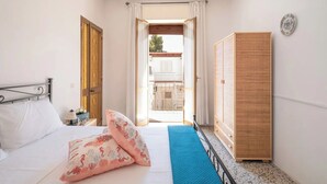 A bedroom with a bed, a wardrobe, a nightstand, and a view of the outside. - Casa Callisto AC vicino al mare (Porto Cesareo)