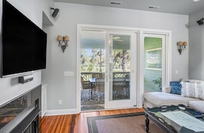 Relax in this stylish living room with a flat-screen TV, sliding glass door to a patio, and comfortable wicker furniture.