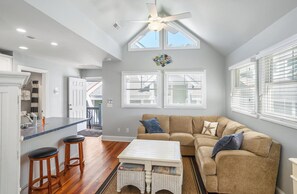 Relax in this inviting living area with a high ceiling, large window, and comfortable sofa.