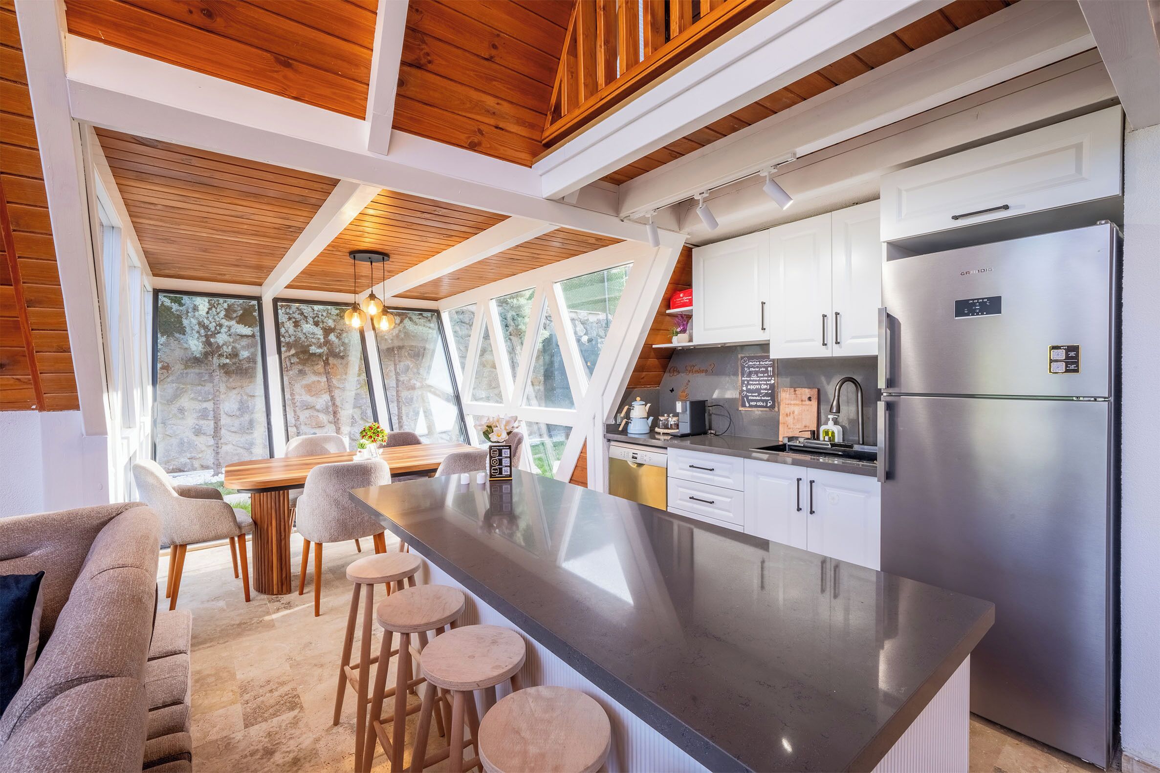 A modern kitchen with a large island, white cabinets, and a stainless steel refrigerator.