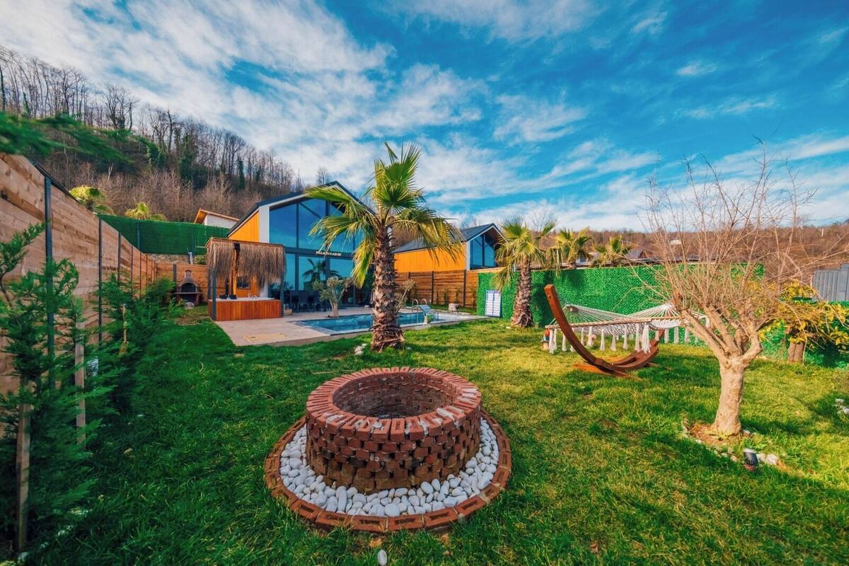 Ein modernes Haus mit Schwimmbad, einem Kamin aus Ziegelsteinen und einer Hängematte.