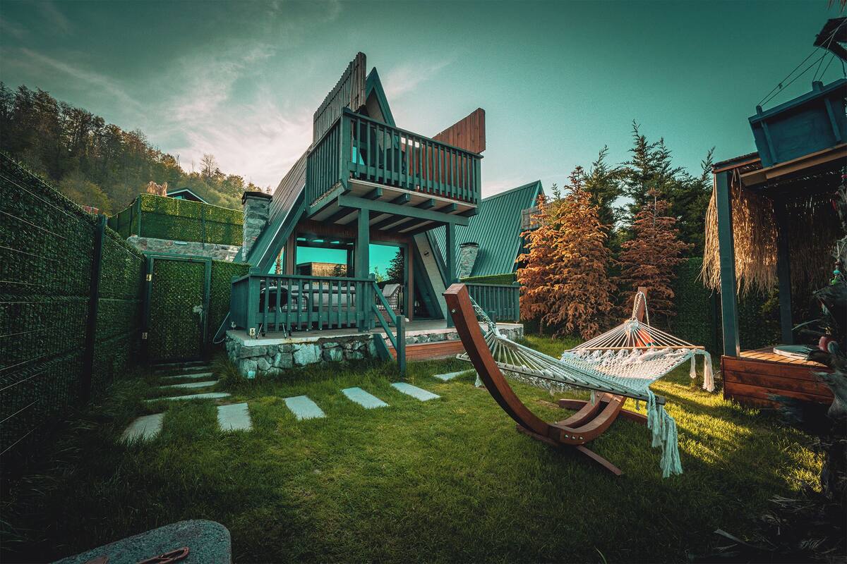 Ein modernes Haus mit einzigartigem architektonischen Design, inklusive einer Holzdielen-Terrasse und einer Hängematte.