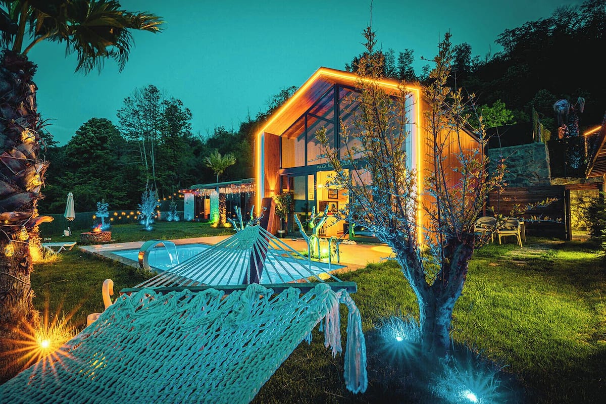 Eine moderne Villa mit Swimmingpool, Hängematte und belebtem Außenbereich.