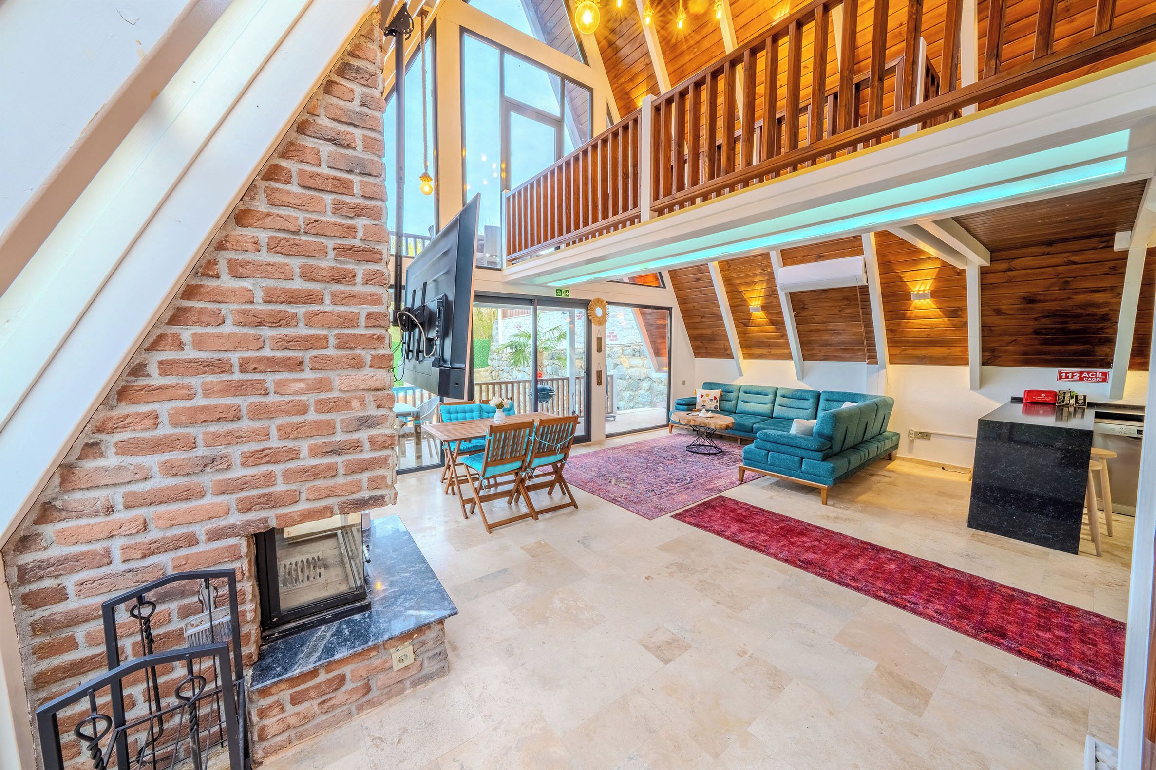 Amplio espacio tipo loft con chimenea, comedor y balcón con barandillas de madera.