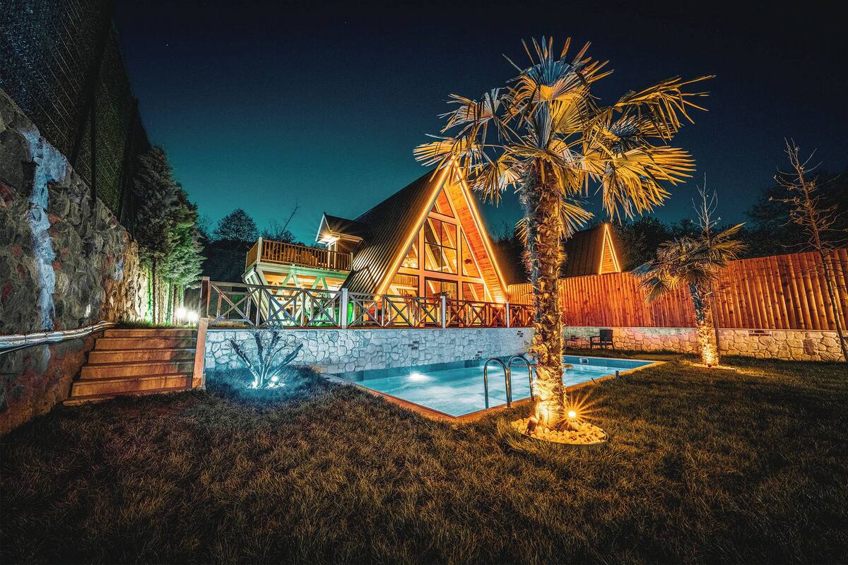 Ein helles, modernes Haus mit Swimmingpool, Steintreppe und Holzterrasse.