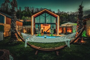 Eine moderne Villa mit großer Glasfassade, einem Pool und einer Hängematte im Vordergrund.