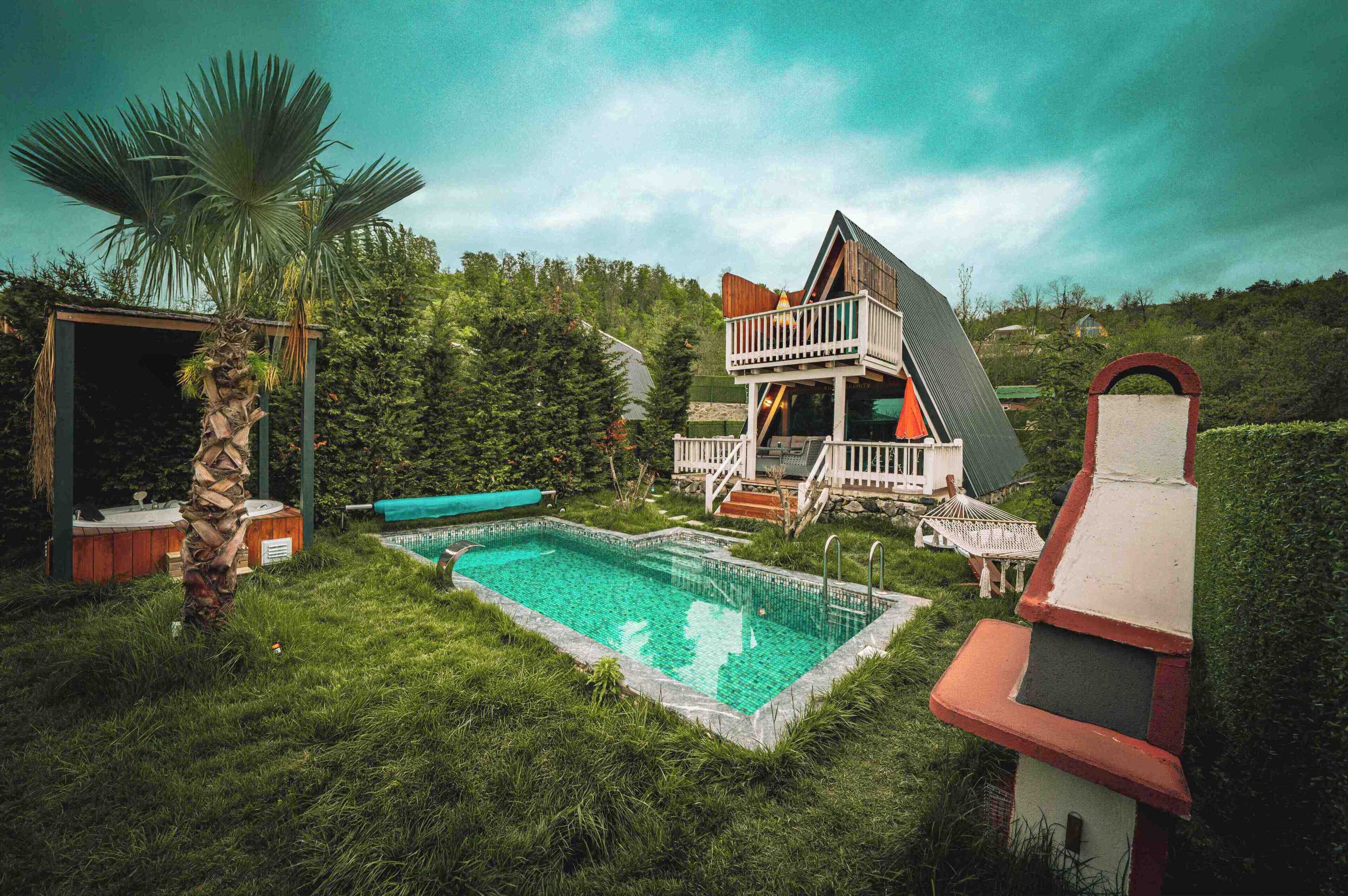 A house with a pool, a deck, and a large tree.