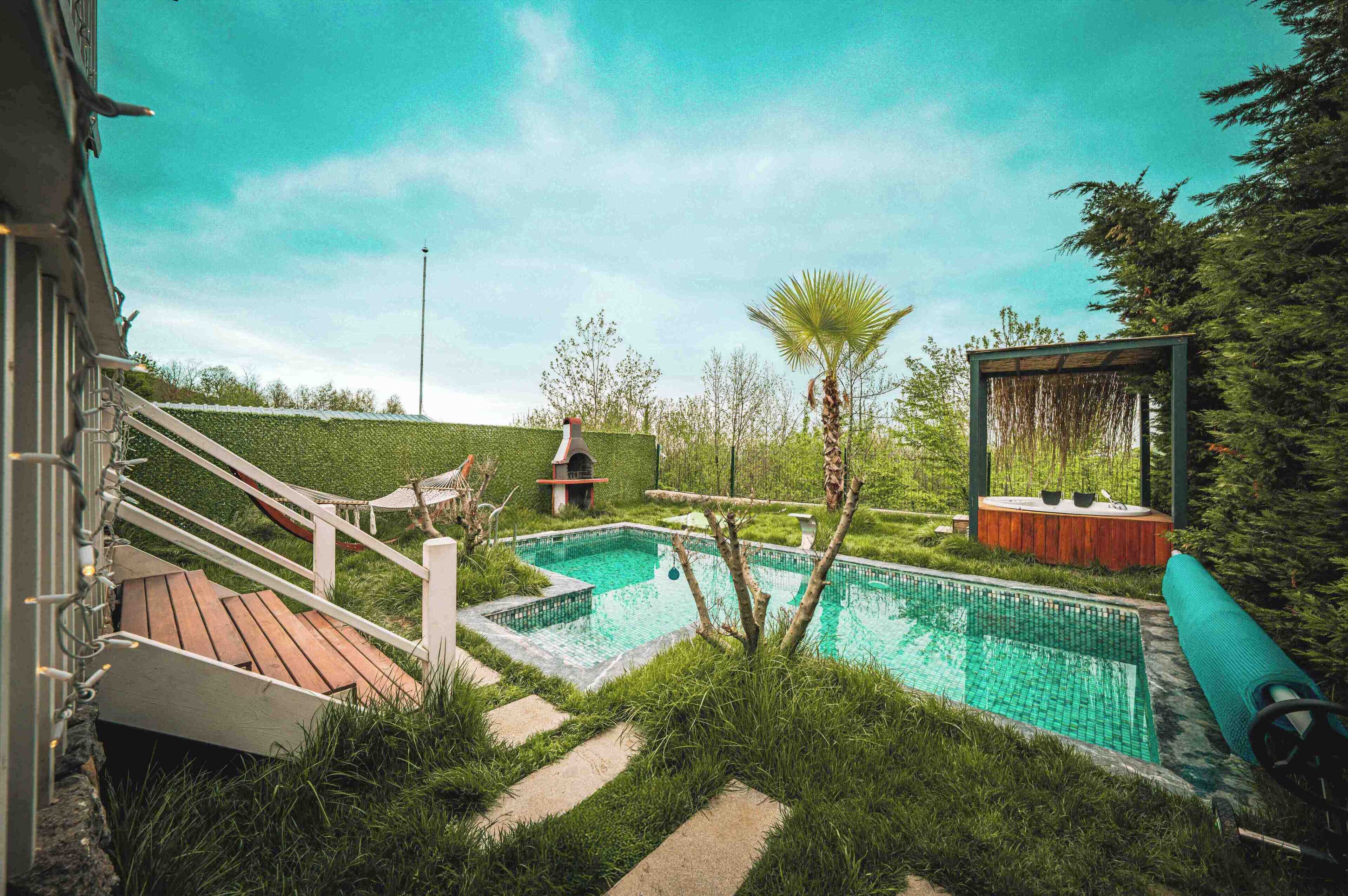 Ein Garten mit Swimmingpool, Holzterrasse und Whirlpool.