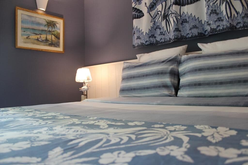 A hotel room with a bed, a nightstand with a lamp, and a framed picture on the wall.