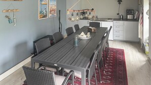 A dining area with a long table, chairs, and a hanging light fixture.