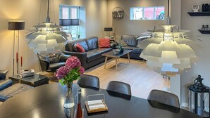 A modern living room with a black leather sofa, a coffee table, and two pendant lights.