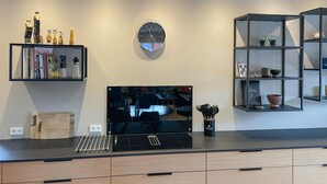 A modern kitchen with a built-in TV, wooden cabinets, and a black countertop.