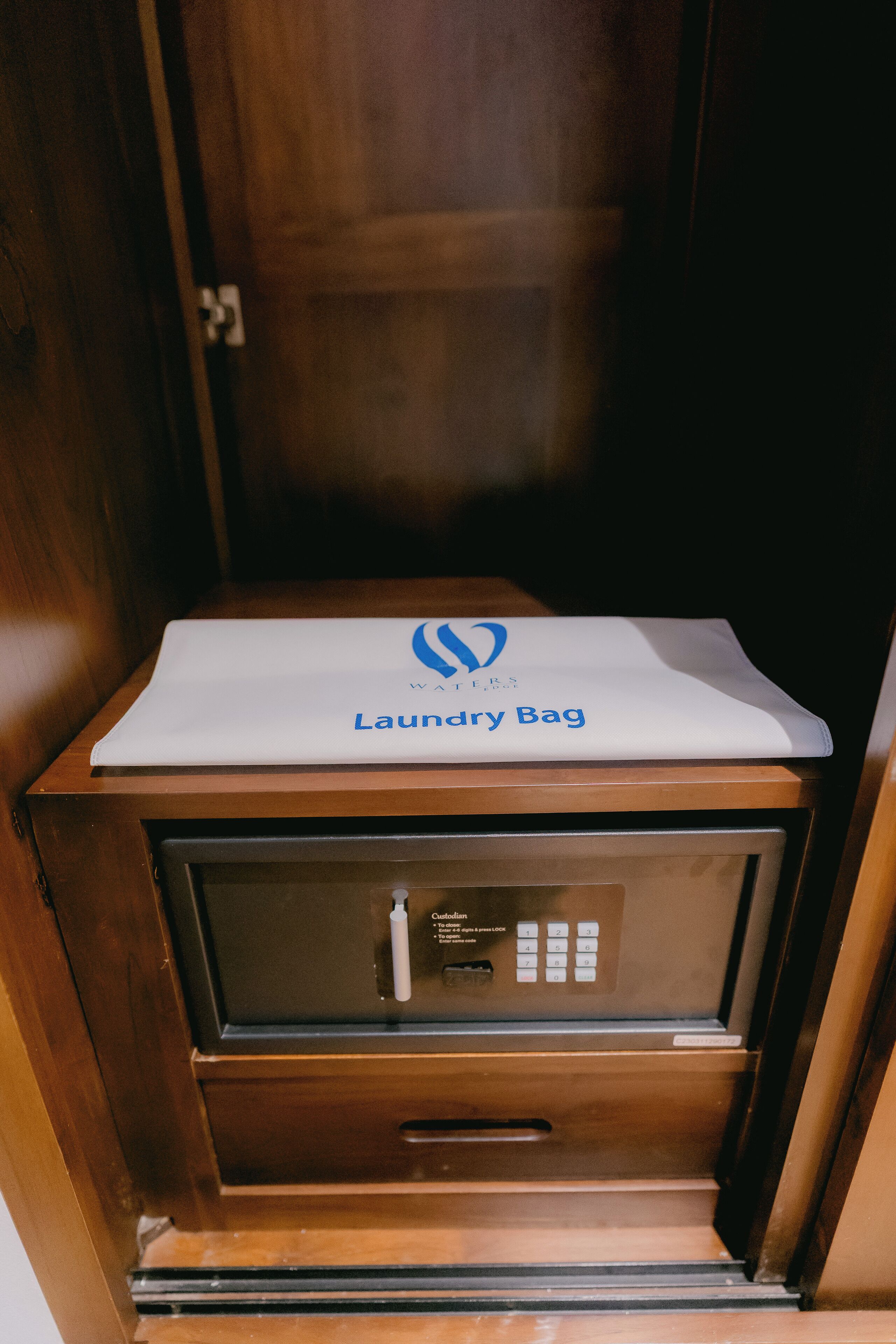 A wooden cabinet with a white laundry bag on top.