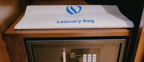 A wooden cabinet with a white laundry bag on top.
